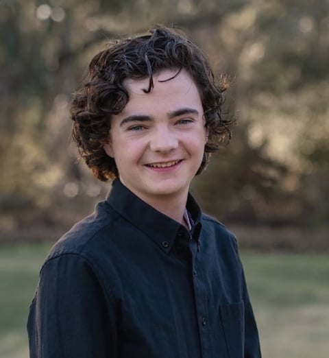 Young boy with curly dark hair wearing a dark blue shirt